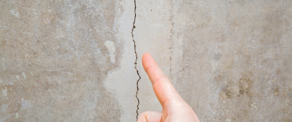 finger pointing at a crack in a wall